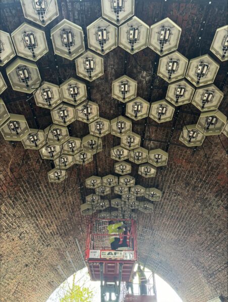 Hexagonal light boxes installed on brick ceiling of viaduct