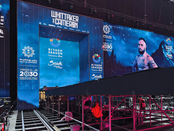Photo of stage build showing metal truss arch structure on a track above a catwalk stage