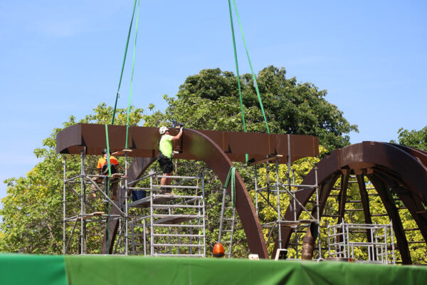Photo of timber structure being built, crane lowering in timber panels and being fitted by on-site team