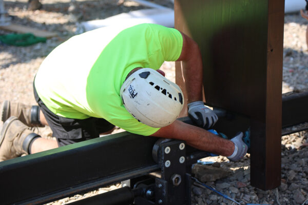 Photo of man installing track upon which a wooden structure will be able to slide left and right