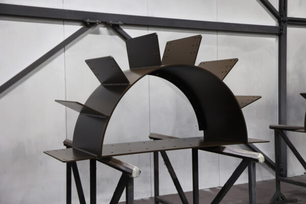 Large-scale metal keystone component with fishplates to which timber will be fixed, shown in workshop