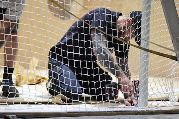 Photo of person kneeling behind netting, stapling netting to floor