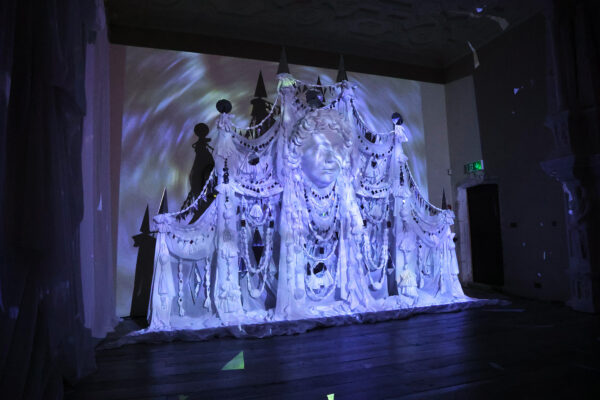 Photo of multi-media artwork projected upon a large-scale sculpture of a face