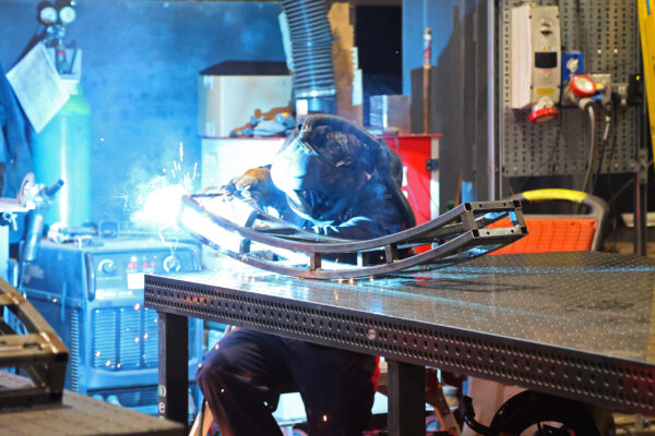 Welder working on a curved metal framework