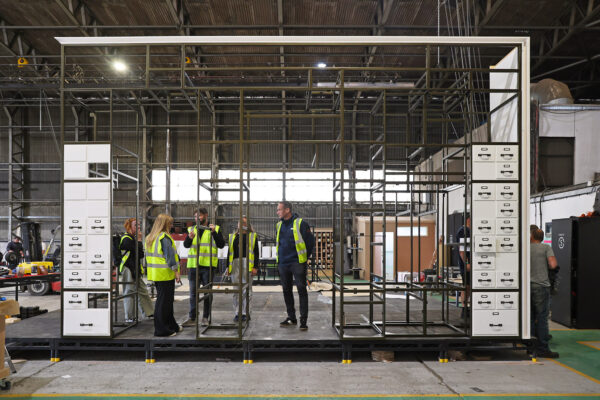 Test build of a metal structure being reviewed by the client and project team in a warehouse setting