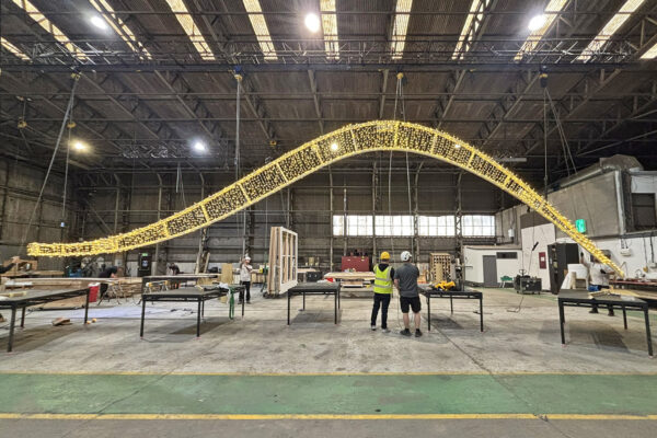 Photo of steel frame covered with fairy lights suspended in the air in a workshop environment